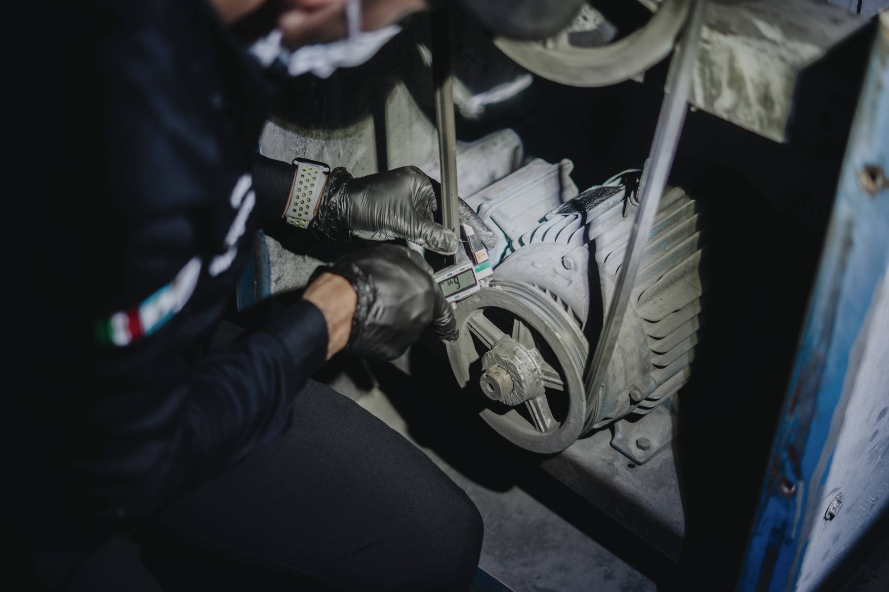 Manos con guantes midiendo una pieza del motor de extracción
